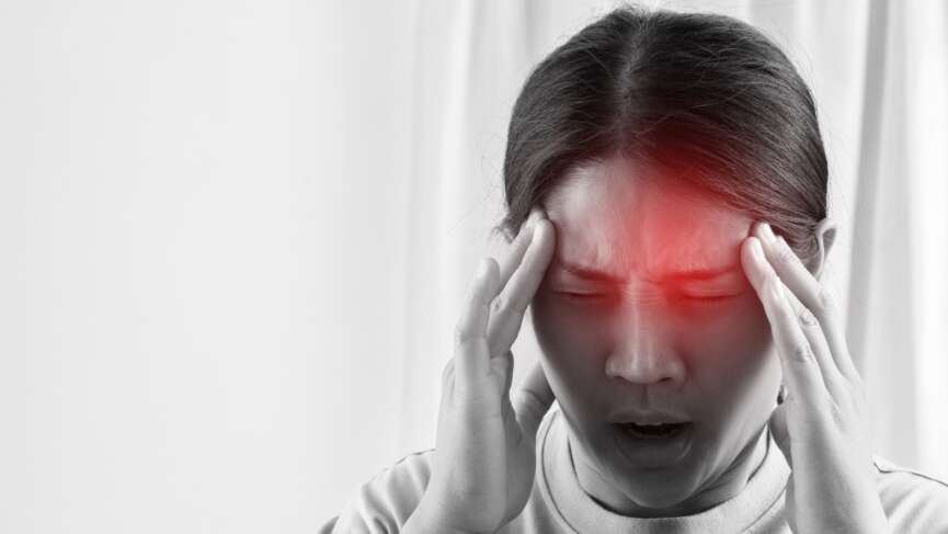 A dizzy Asian woman holding head, experiencing a headache, and seeking for treatment