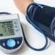 An old senior man using medical device to measure blood pressure suffering from hypertension