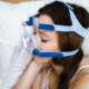 woman sleeping in bed with sleep apnea using a CPAP machine
