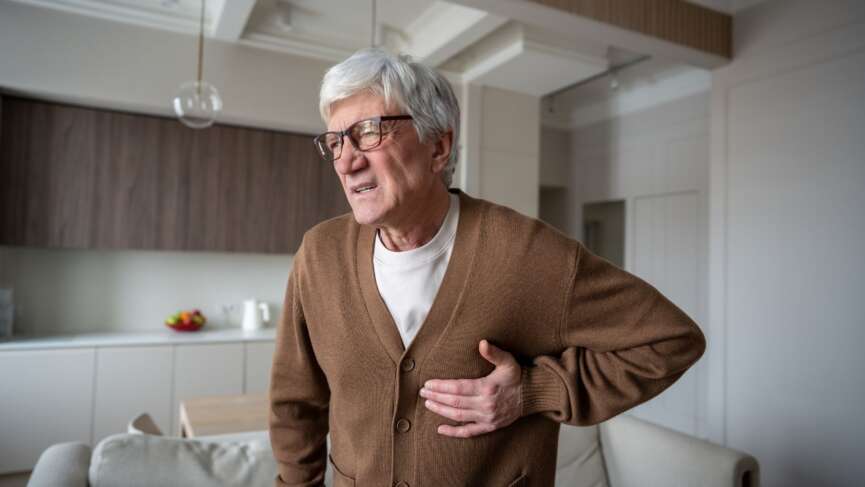 A worried old man clutching chest in pain, suffering from atrial fibrillation