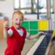 Cute boy playing piano with down syndrome in a red sweater