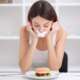 Close-up face of a young, beautiful, sad Latina woman with mouth sealed on stick tape representing anorexia nervosa