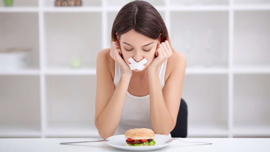 Close-up face of a young, beautiful, sad Latina woman with mouth sealed on stick tape representing anorexia nervosa