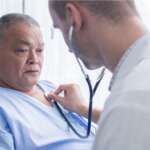 male doctor hold a stethoscope and listen to mature male patient's heartbeat in private clinic who is suffering from reverse coronary artery disease
