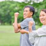 Middle-aged man and woman doing stretching exercises outside, representing the benefits of exercise on mental health