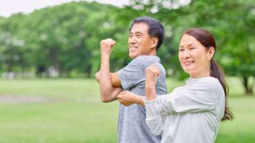 Middle-aged man and woman doing stretching exercises outside, representing the benefits of exercise on mental health