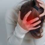 A young girl holding her head with both hands with severe headache, representing the types of brain stroke