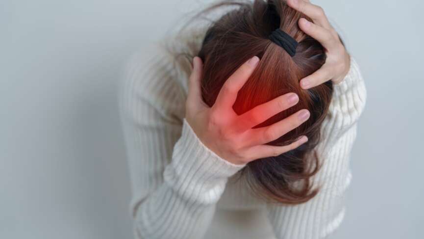 A young girl holding her head with both hands with severe headache, representing the types of brain stroke