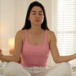 young woman meditating, doing yoga, breathing exercises with eyes closed for better mental health