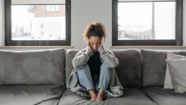 woman with a headache, stress, burnout, anxiety, tiredness, or thinking in house representing chronic fatigue syndrome
