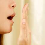 female testing her breath with her hand representing stinky and causes of bad breathe