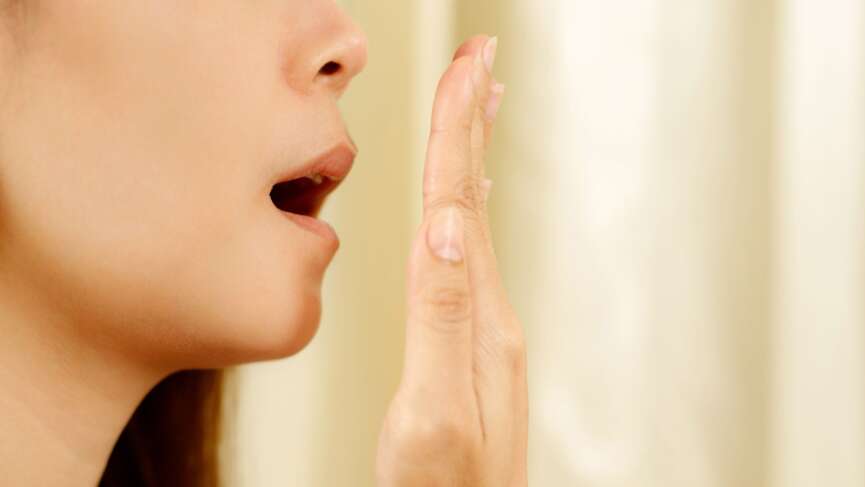 female testing her breath with her hand representing stinky and causes of bad breathe