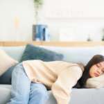 A young female sleeping on the couch, representing side effects of lack of sleep