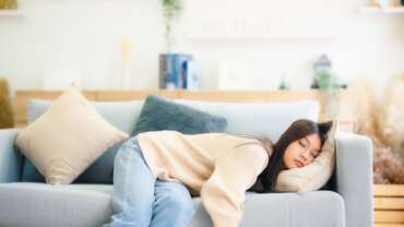 A young female sleeping on the couch, representing side effects of lack of sleep
