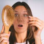 A woman with hair loss and a comb representing hair loss and baldness problems