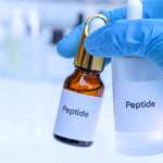 a man holding a two bottle of peptides with a blue gloves for hair loss treatment