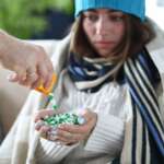 A young ill girl wearing a robe and winter hat with full of medicine in her hand, representing the causes of hypothermia