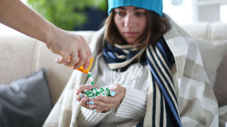 A young ill girl wearing a robe and winter hat with full of medicine in her hand, representing the causes of hypothermia