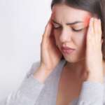 A hardworking woman suffer huge migraine, feeling pain in head representing phases of migraine headache
