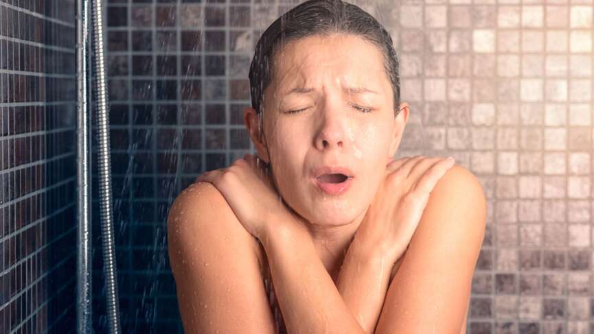 woman screaming in the shower under cold water jet, representing the benefits of cold shower