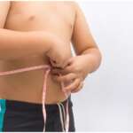 A boy holding measuring tape, representing effects of child obesity