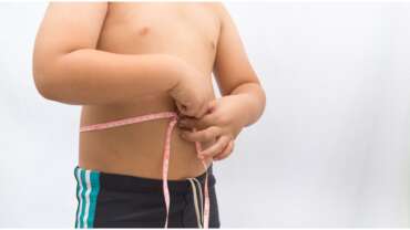 A boy holding measuring tape, representing effects of child obesity