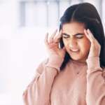 a frustrated young female struggling with a migraine