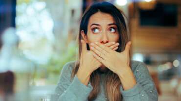 Young woman suffering from burping in middle of the street