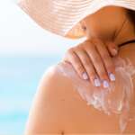 A young beautiful woman applying sunscreen