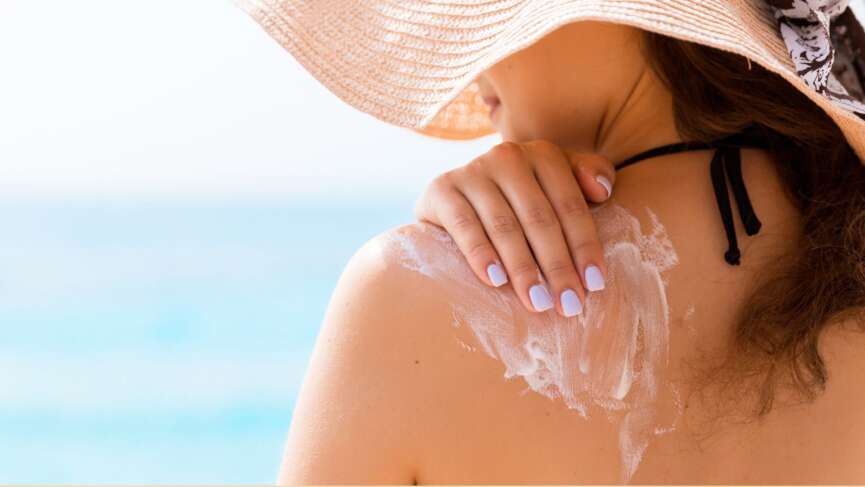 A young beautiful woman applying sunscreen