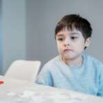 Cute boy sitting at home presenting symptoms of autism
