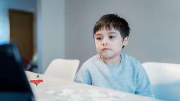 Cute boy sitting at home presenting symptoms of autism