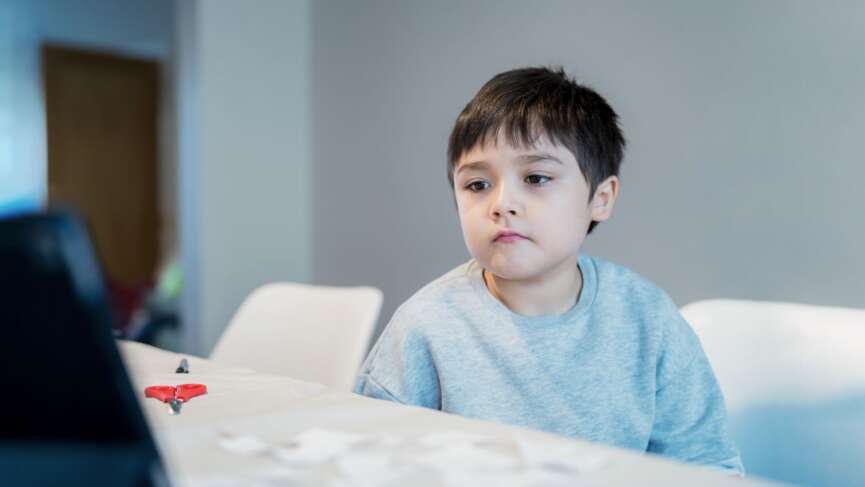 Cute boy sitting at home presenting symptoms of autism