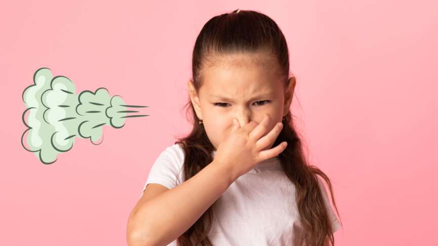 A little girl in a t-shirt is keeping hand on mouth and looking disgusted due to smelly fart around