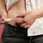 A woman with diabetes making insulin injection into her belly at home for the medications for type 1 diabetes