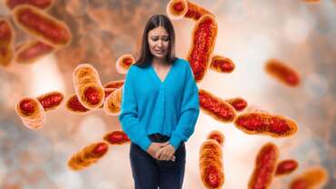 A young pretty caucasian woman with black hair dressed in a stylish blue cardigan feels uncomfortable due to how bacterial vaginosis