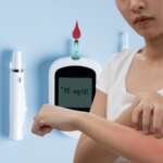 A woman looking at her skin, which can be a sign of diabetes and high diabetes result in glucometer in the background
