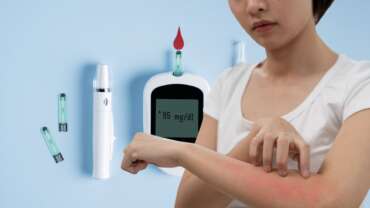 A woman looking at her skin, which can be a sign of diabetes and high diabetes result in glucometer in the background