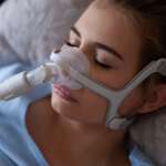 A woman wearing CPAP mask for sleep apnea treatment, related to types of sleep apnea
