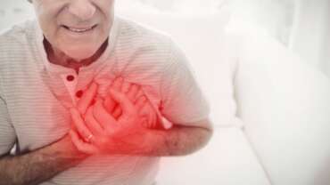 Old man clutching chest with red highlight suggesting heart attack or symptoms of heart attack