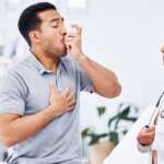 A young man using asthma inhaler for respiratory relief following asthma action plan