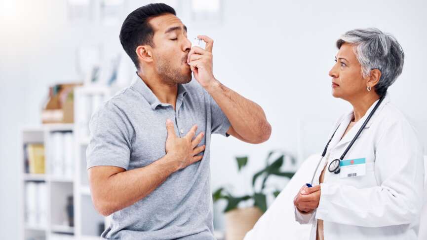 A young man using asthma inhaler for respiratory relief following asthma action plan