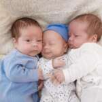A portrait of newborn triplets is lying in the bed. Causes of Multiple Pregnancy concept