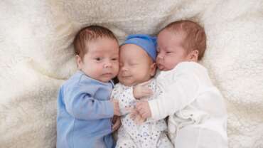 A portrait of newborn triplets is lying in the bed. Causes of Multiple Pregnancy concept