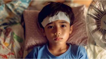 Febrile seizures in a child concept. A boy resting in bed with cooling gel patch on forehead, suffering from a fever