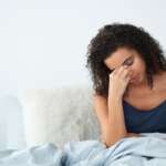 Adult woman is sick, sitting on her bed representing causes of iron deficiency anemia concept