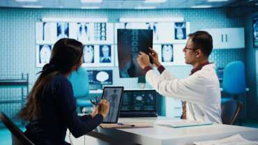 A CT scan radiologist showing an X-ray to girl in computed scanning room. CT Scan and PET Scan concept
