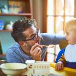 Dad feeding his child with a spoon. diet plan for child concept