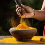 Indian spice turmeric powder splashing from a stone mortar in closeup. health benefits of turmeric concept