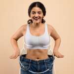 A beautiful young woman with black hair holding her jeans of a much bigger size. facts about weight loss concept